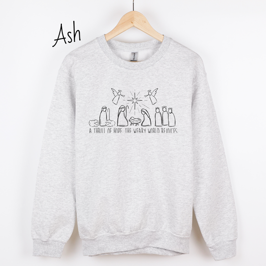 Hand drawn nativity scene with the words "A thrill of hope, the weary world rejoices" written underneith. Design is black on an ash colored sweatshirt.