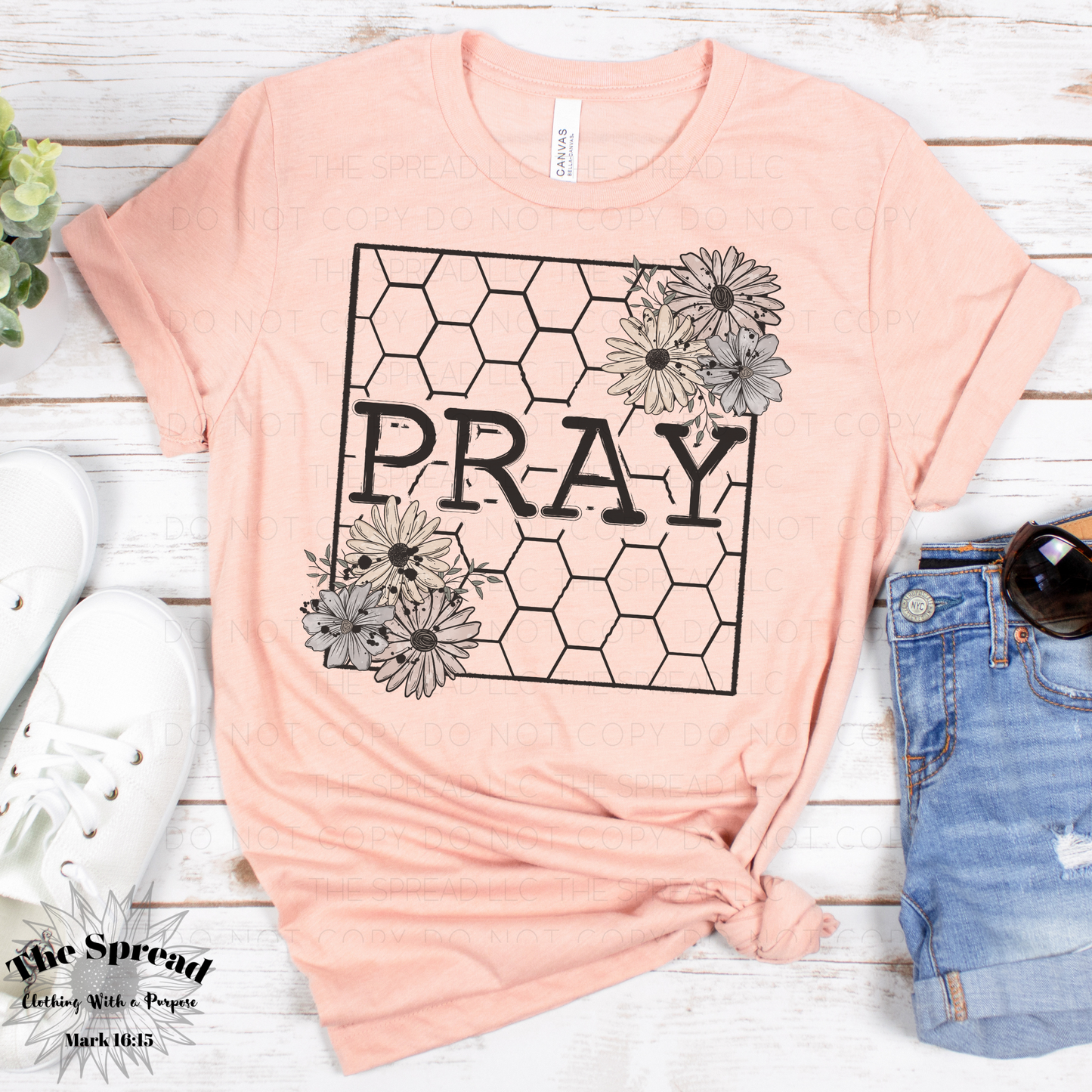 The Pray Honeycomb Short Sleeve Tee, a heather clay colored t-shirt made from Airlume combed cotton, features PRAY in bold within a honeycomb pattern. Floral designs accent the corners.