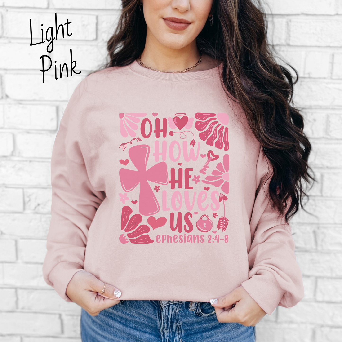 "Oh how He loves us Ephesians 2:4-8" written in various shades of pink with florals and a cross on a light pink sweatshirt.