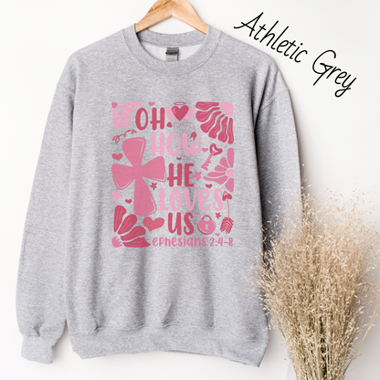 "Oh how He loves us Ephesians 2:4-8" written in various shades of pink with florals and a cross on a light grey sweatshirt.
