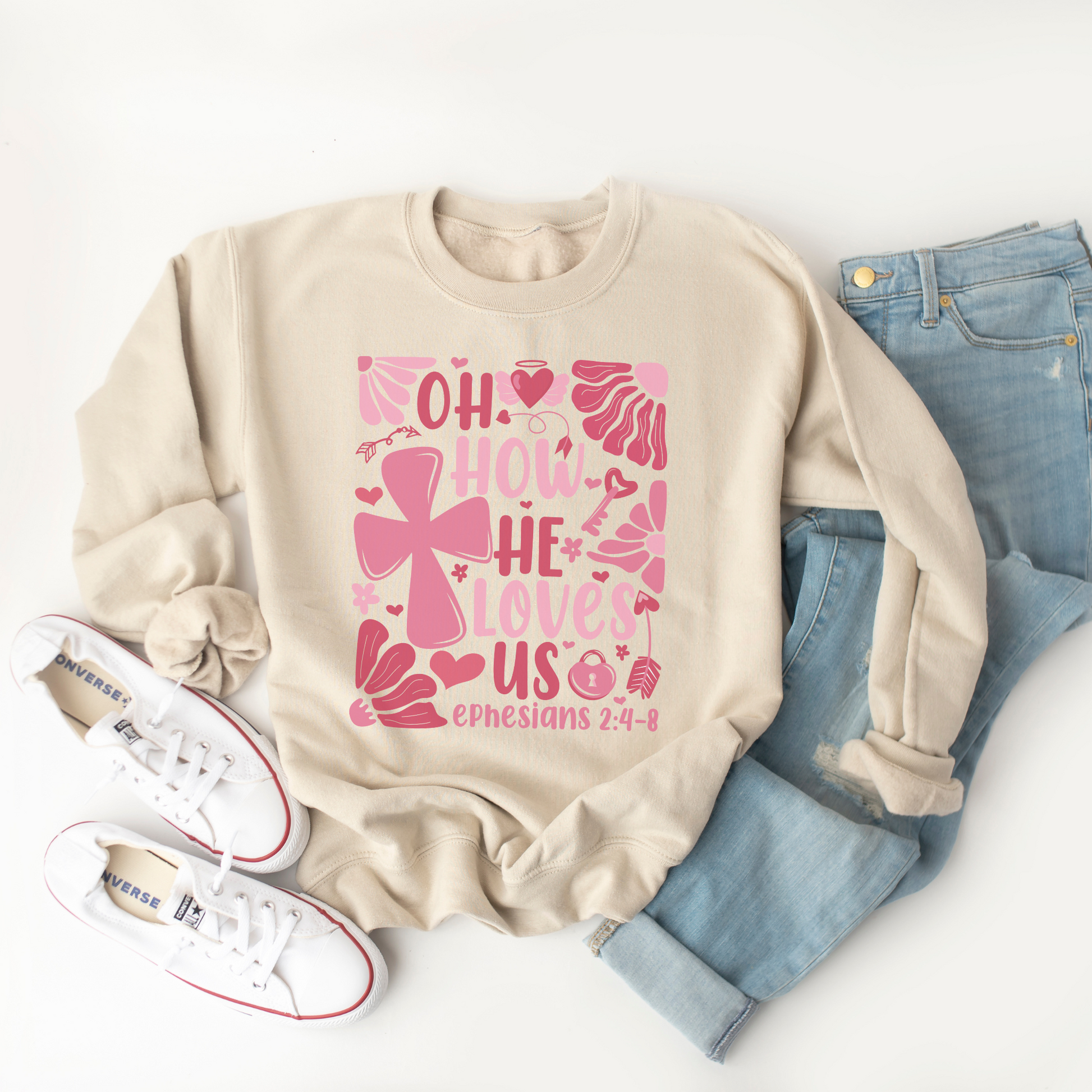 "Oh how He loves us Ephesians 2:4-8" written in various shades of pink with florals and a cross on a cream colored sweatshirt.