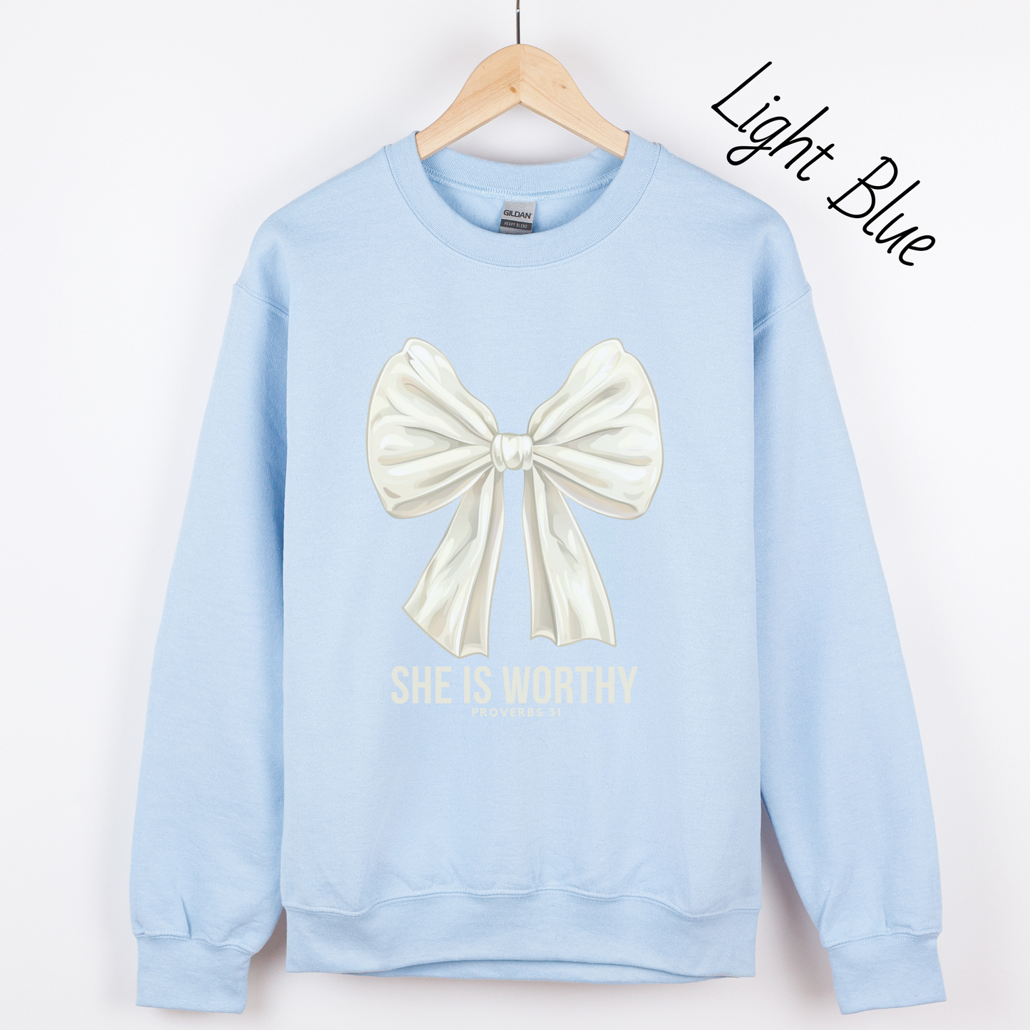 Large white bow with the words "She is Worthy Proverbs 31" on a light blue sweatshirt.