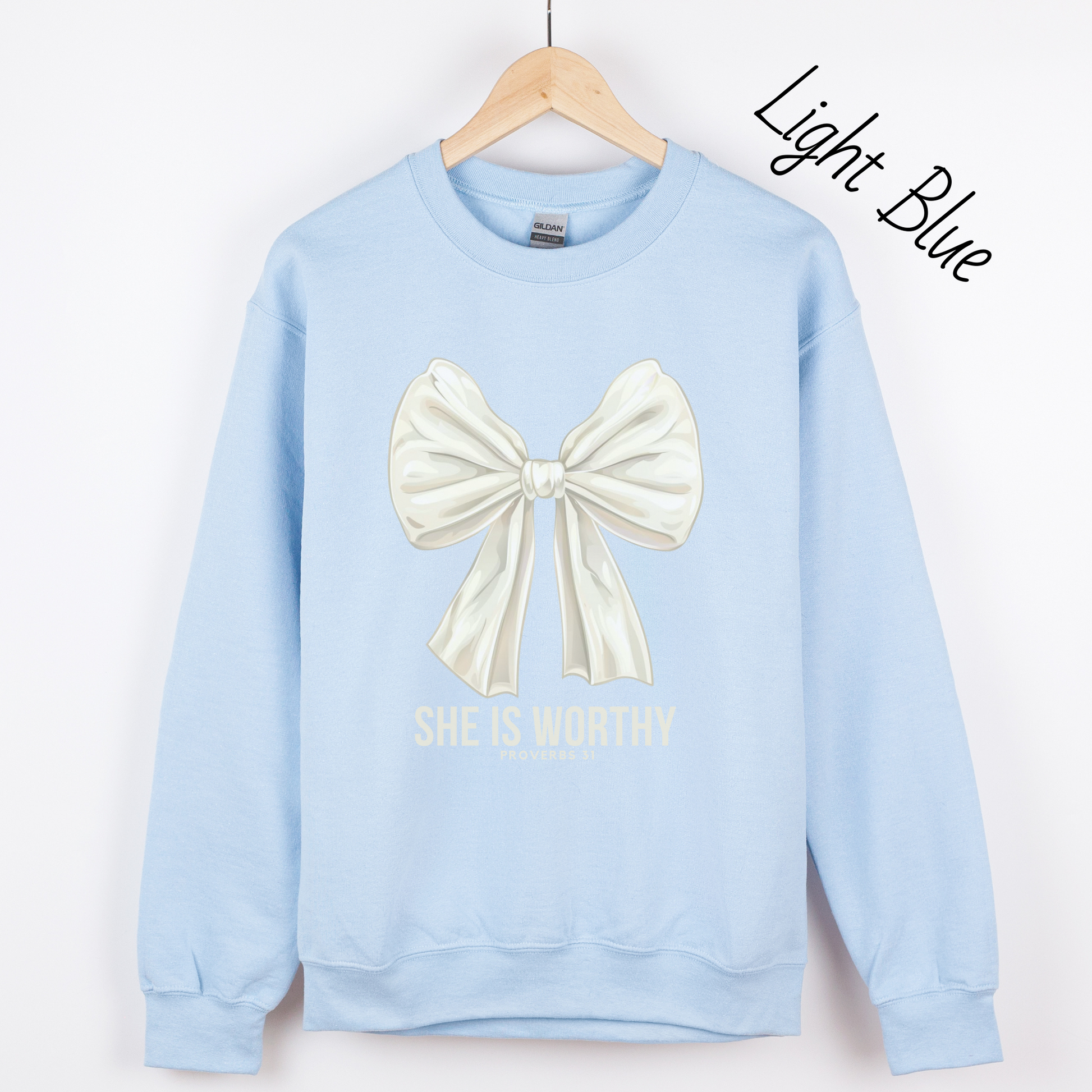 Large white bow with the words "She is Worthy Proverbs 31" on a light blue sweatshirt.