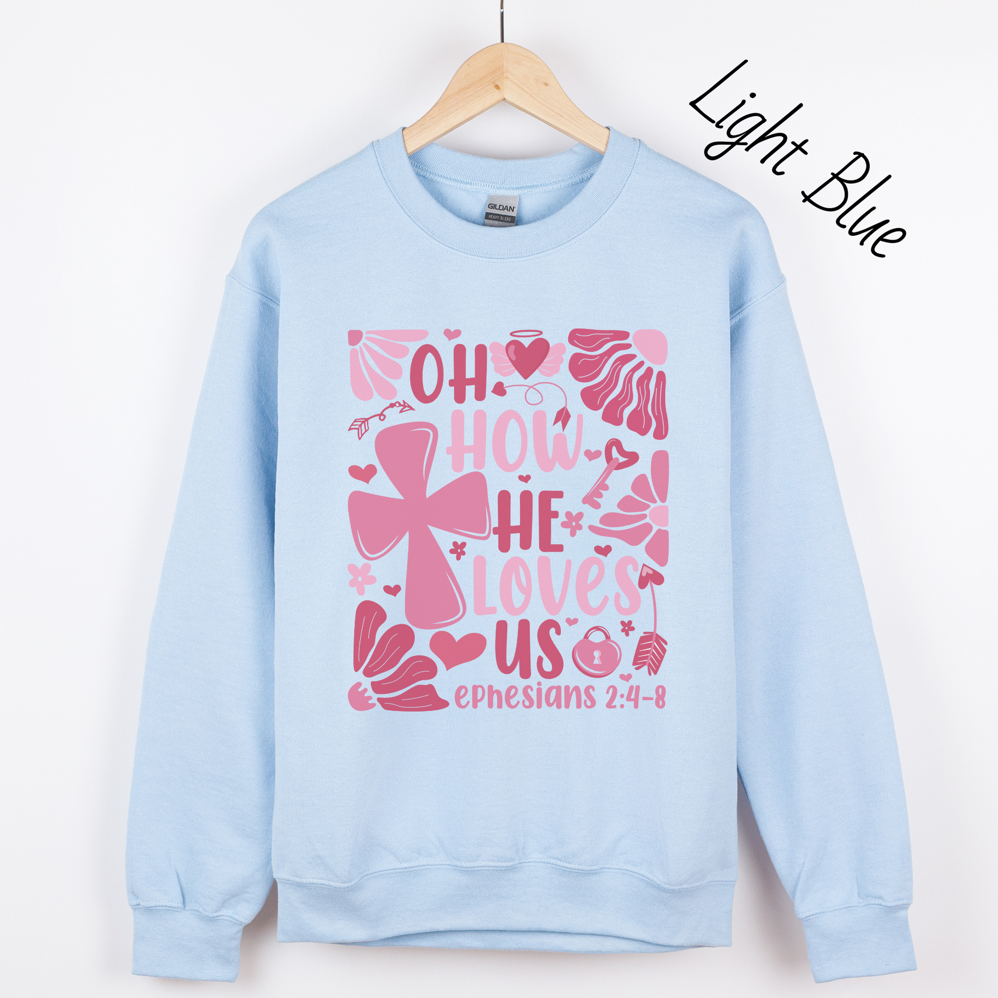 "Oh how He loves us Ephesians 2:4-8" written in various shades of pink with florals and a cross on a light blue sweatshirt.